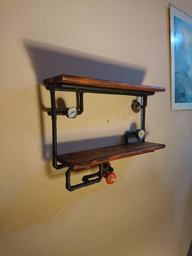 Steampunk shelving unit with wood shelves and black industrial pipe fittings mounted on a wall