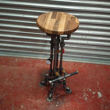 Industrial steampunk bar stool with wooden seat and metal pipe base, exposed fittings.