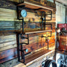 Steampunk shelving unit with wood shelves, black metal pipes, and gauge details on rustic wall