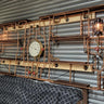 Industrial steampunk shelving unit with copper pipes, vintage gauge, lantern lights, and wood shelves.