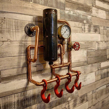 Steampunk coat rack with copper pipes, red hooks, and industrial gauge on rustic wood wall