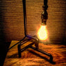 Industrial pipe style table lamp with exposed vintage bulb on wooden surface