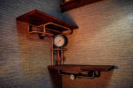 Steampunk industrial shelving unit with wood shelves, copper pipes, gauges, and valve on wall