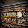 Industrial steampunk shelving unit with wooden shelves, black metal pipes, and vintage pressure gauge on a rustic brick wall.