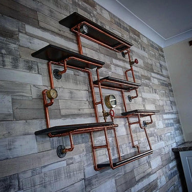 Steampunk industrial shelving unit with copper pipes, gauges, and black shelves on a wood wall