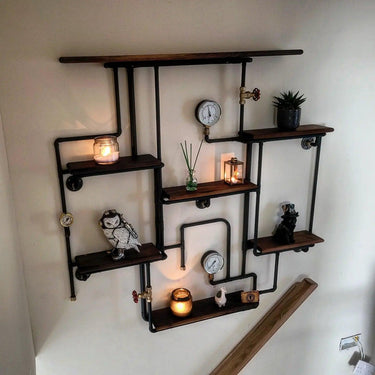 Steampunk industrial shelving unit with pipe frame, wood shelves, gauges, candles, and decor items.