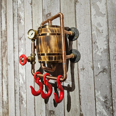 Industrial steampunk wall hook rack with wood barrel, metal pipes, gauge, and red hooks on wood panel