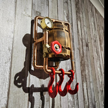 Steampunk industrial wall hook with copper pipes, pressure gauge, red valve, and red hooks