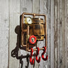 Handmade steampunk wall hook with red pipe hooks, gauge, and wood barrel on rustic wall